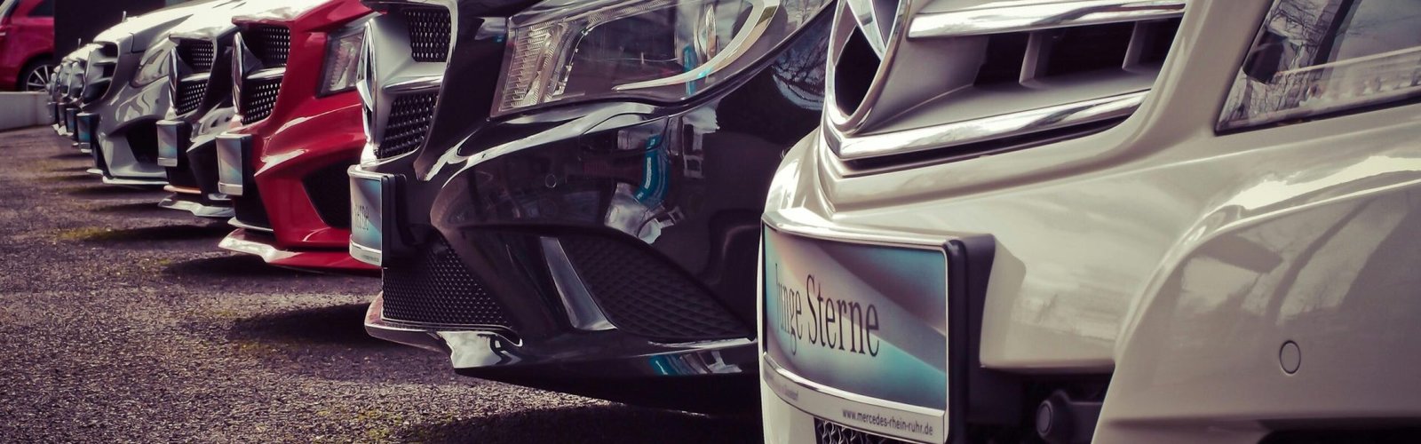 Luxury cars lined up at an outdoor dealership, showcasing sleek designs.